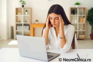 Femeie stresată la birou, cu dureri de cap, simbol al stresului cronic și al epuizării profesionale